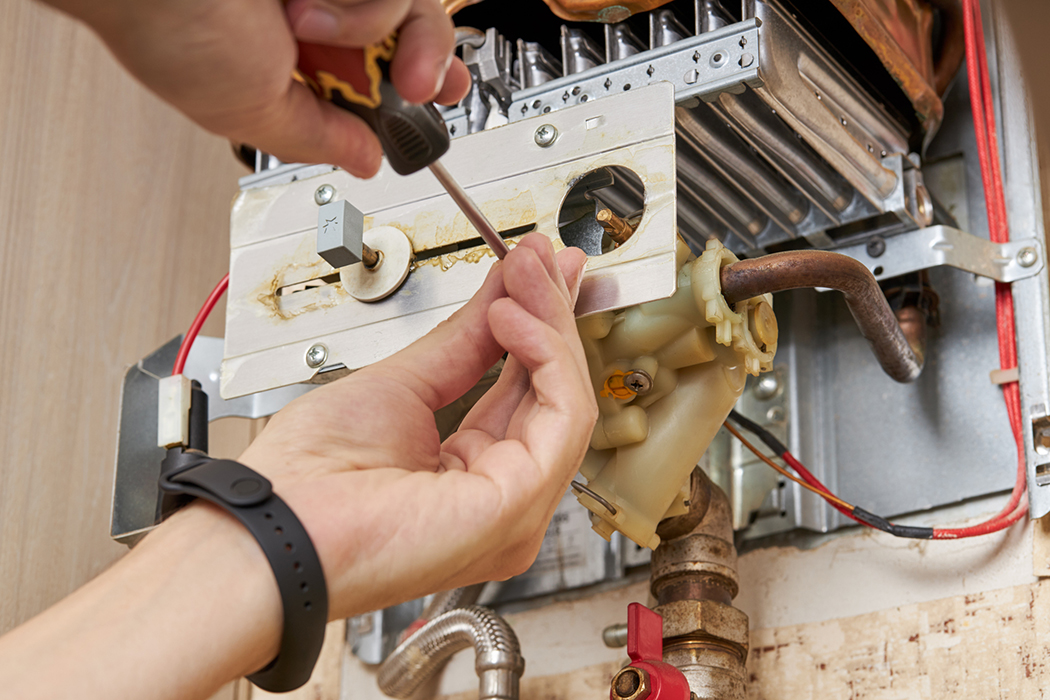 Technician making an adjustment to a water heater